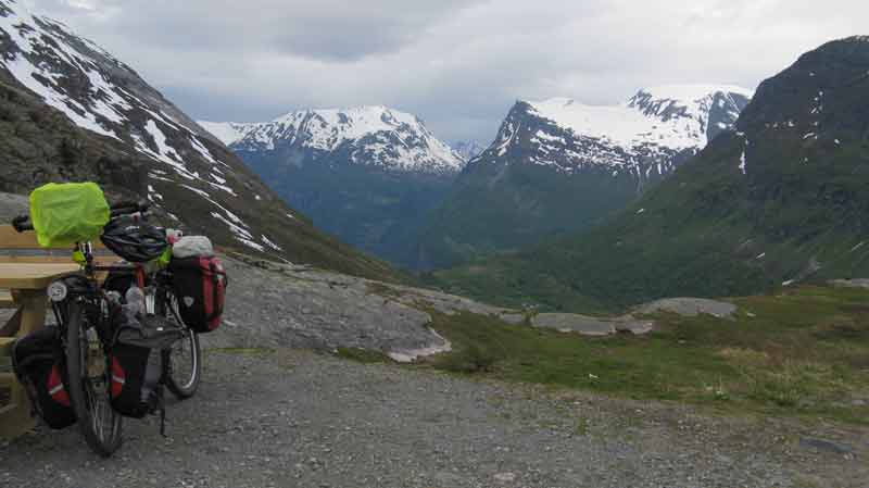 touring bike next to a bench with Norwegian mountains behind
